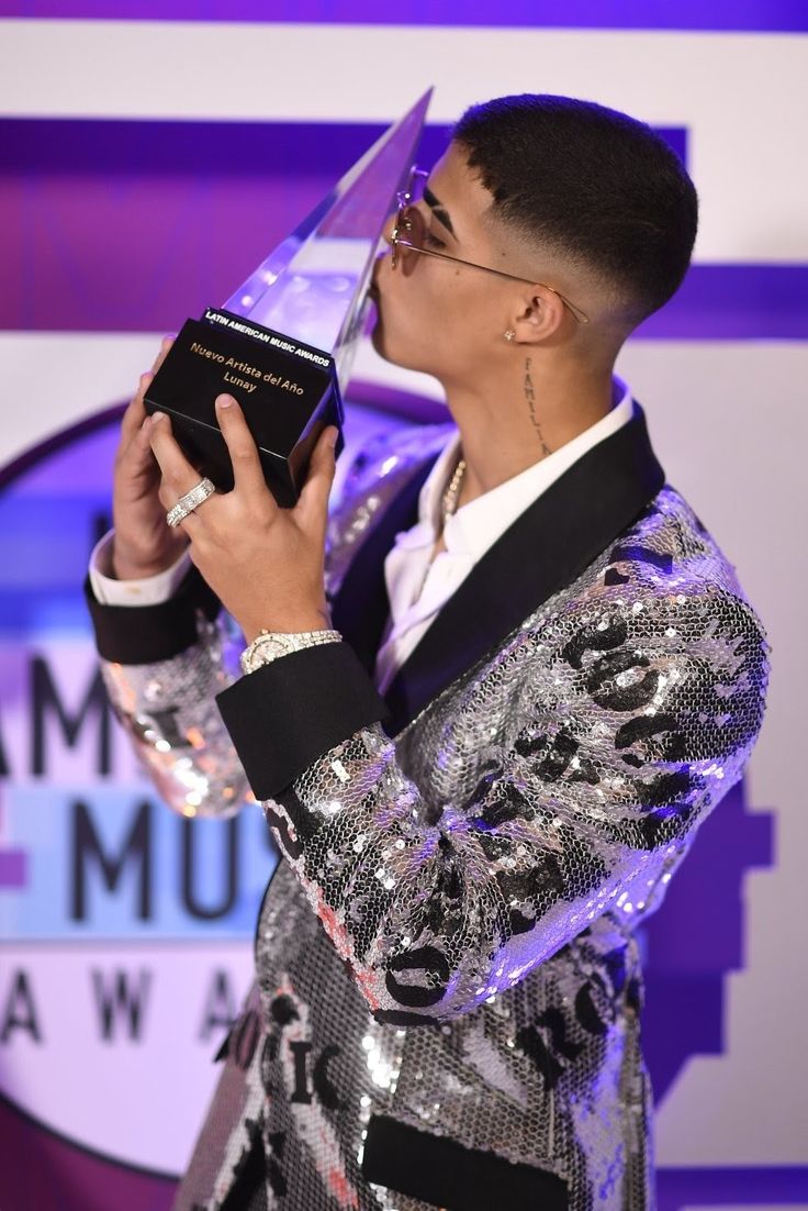 a man holding an award in his hand while wearing a suit and tie on stage