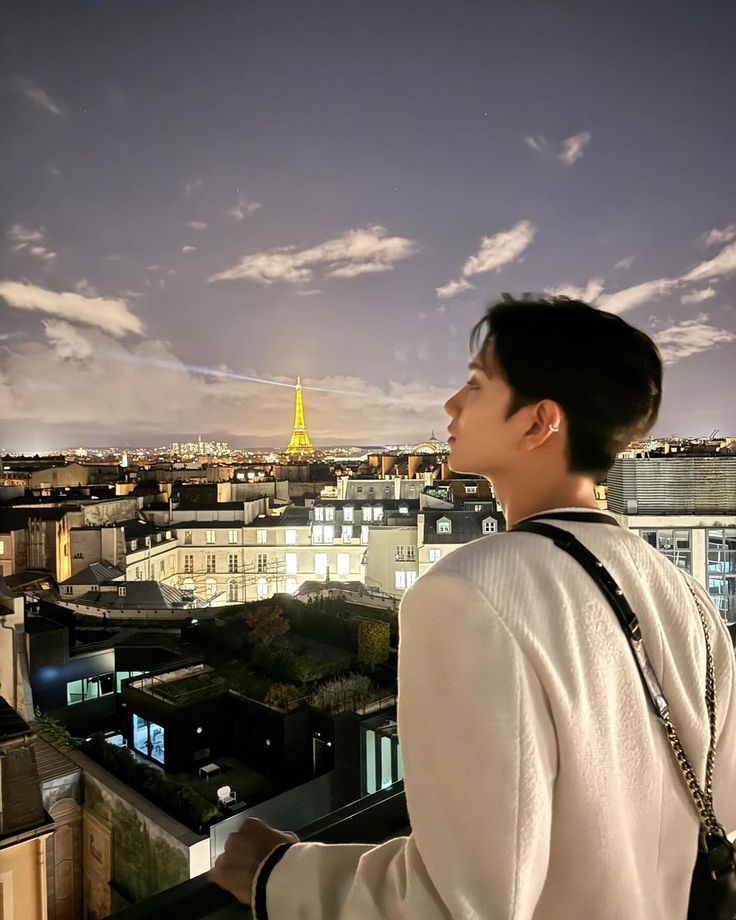 a man standing on top of a tall building looking at the city below his head