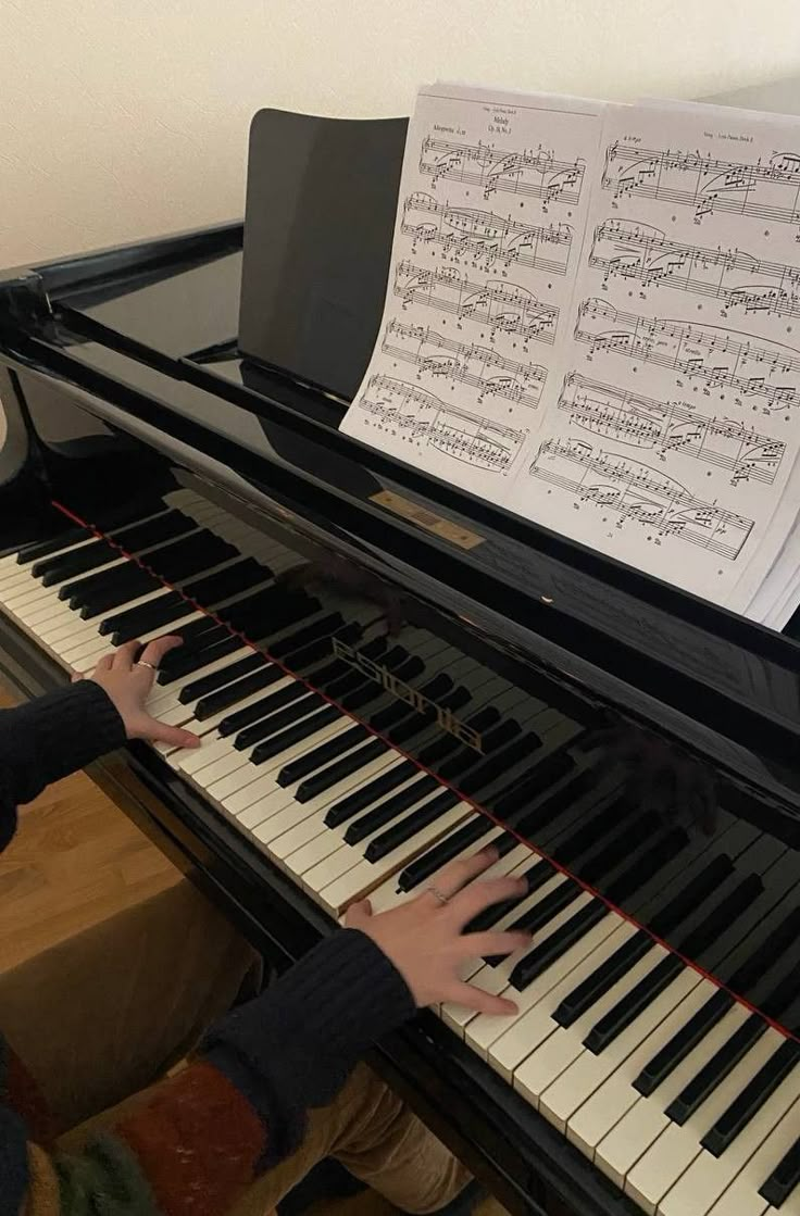 a young boy is playing the piano with sheet music