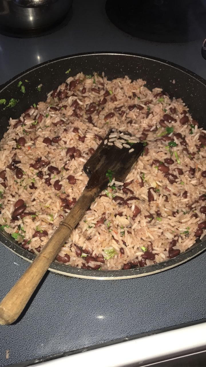 a pan filled with rice and meat sitting on top of a stove next to a spatula