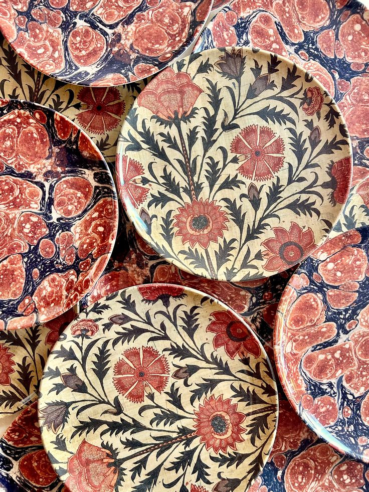 several red and blue plates sitting on top of each other with designs on the sides