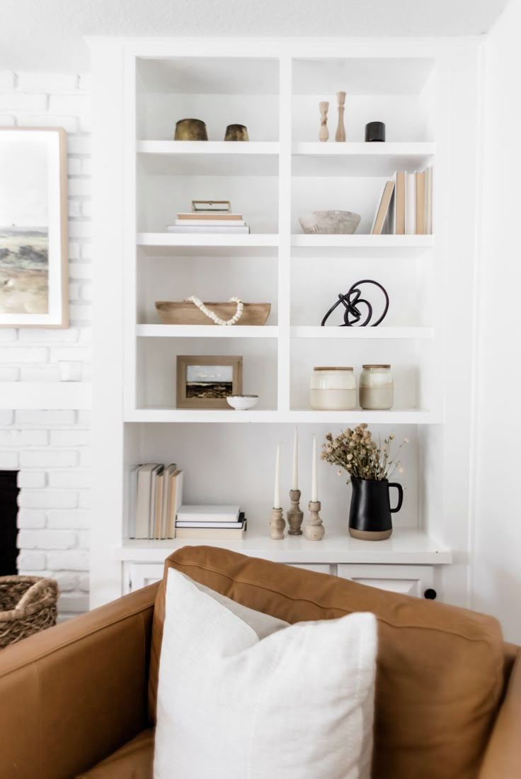 a white bookcase with books and vases on it's shelves in a living room