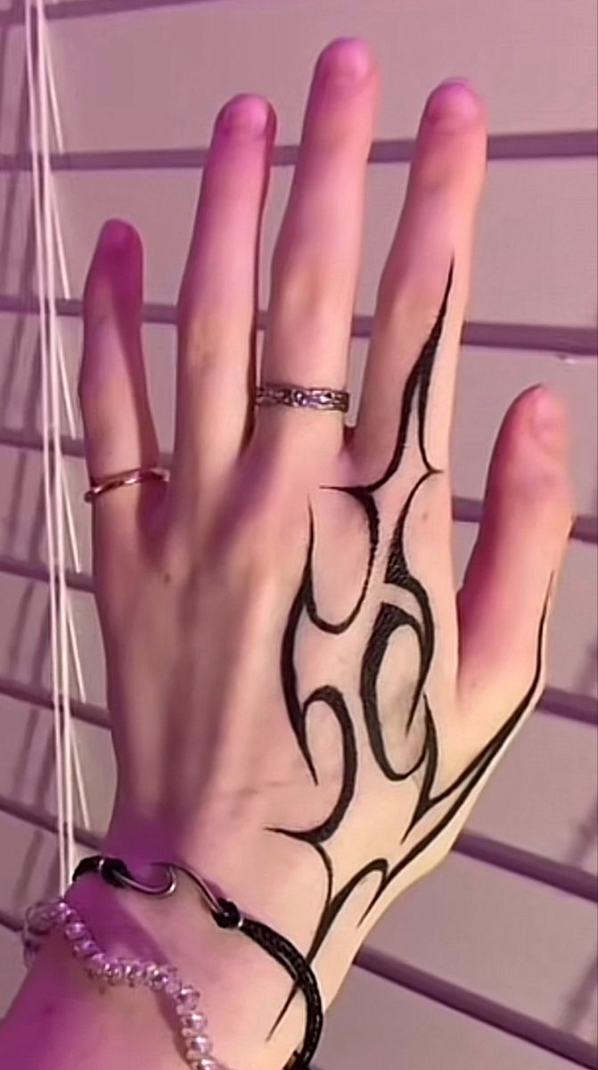 a woman's hand with black and white tattoos on it, next to blinds