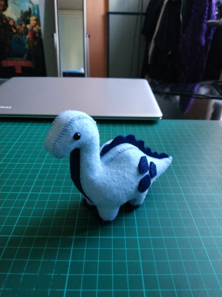 a stuffed animal sitting on top of a green cutting board next to a laptop computer