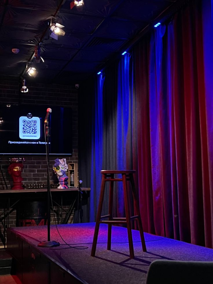 the stage is set up for an event with red and blue curtains, stools, and lights