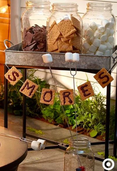 some jars with marshmallows and cookies in them sitting on a table outside