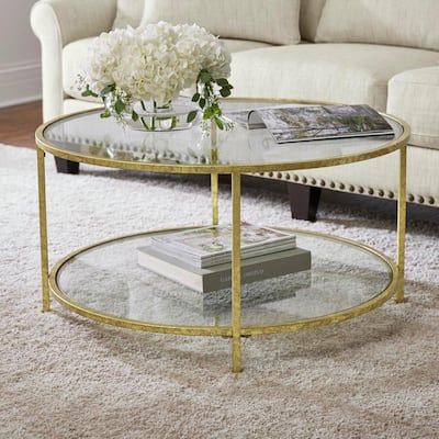 a coffee table with flowers on top in front of a couch and white rugs