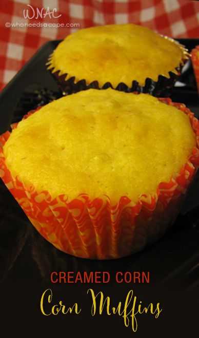 two corn muffins sitting on top of a black tray next to a red and white checkered tablecloth