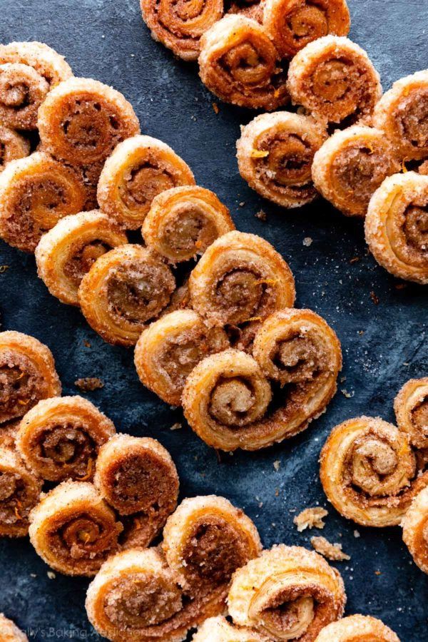 several cinnamon rolls are arranged on a blue surface with powdered sugar sprinkles