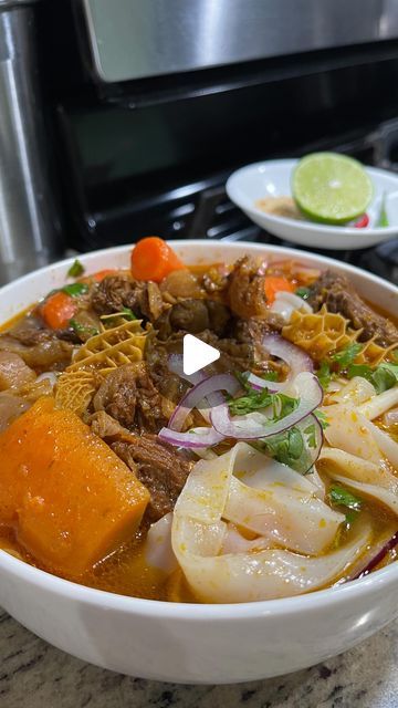 a bowl filled with meat and vegetables on top of a counter next to a stove