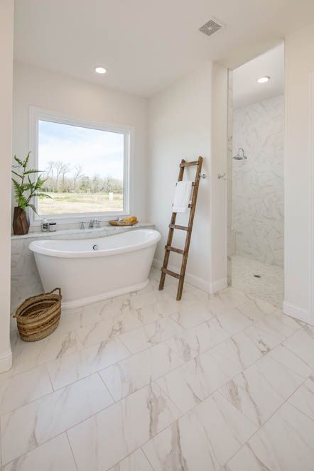 a white bathroom with a ladder in the corner and a large bathtub next to it