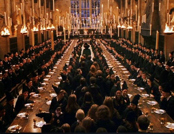 a large group of people sitting at long tables in a room with chandeliers