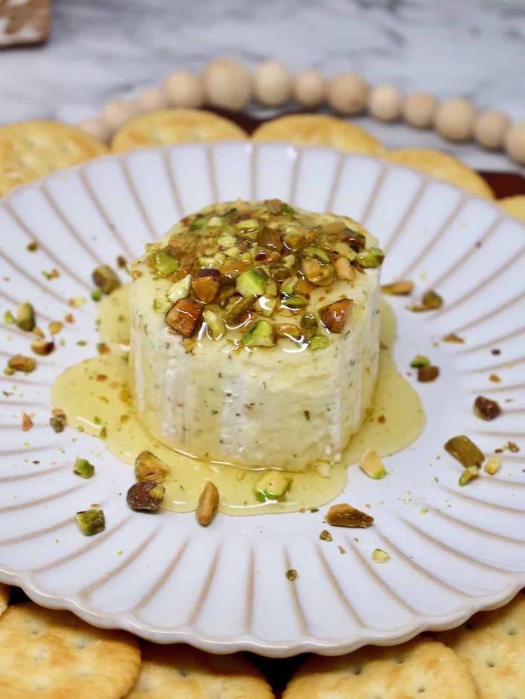 a white plate topped with a cake covered in toppings next to some crackers