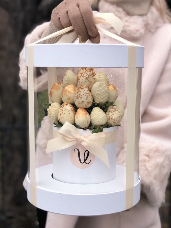 a teddy bear holding a white box filled with chocolates