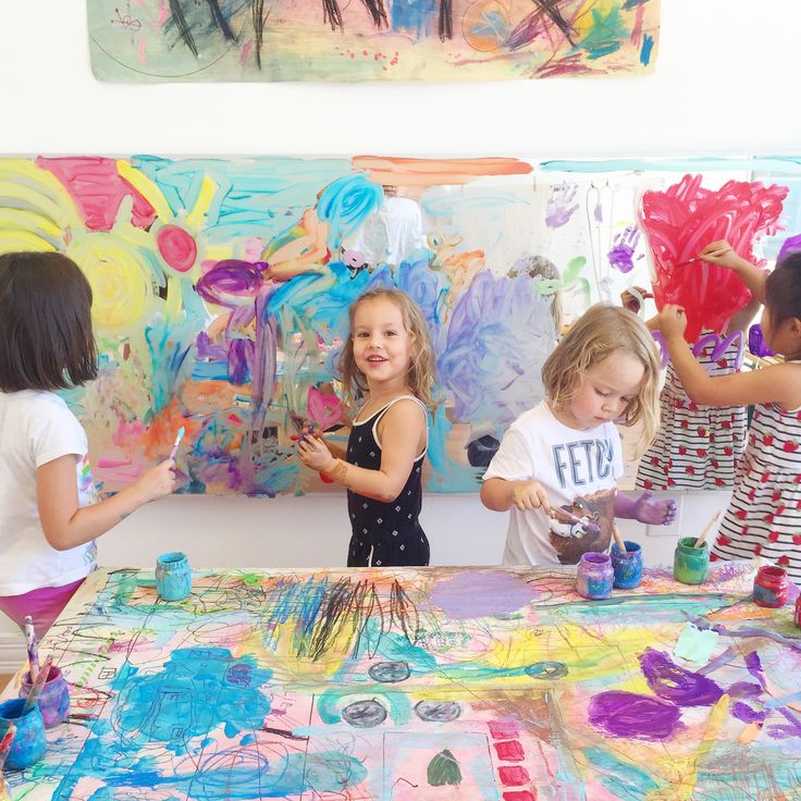 children are painting on canvass in an art class