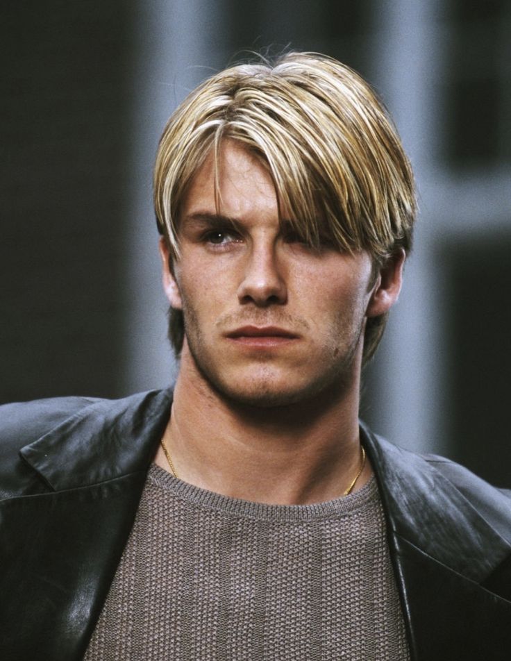 a young man with blonde hair wearing a black leather jacket and looking at the camera