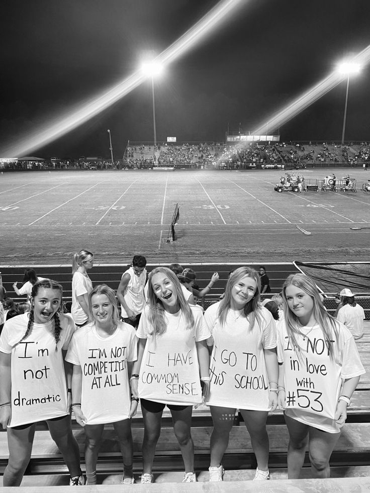 a group of young women standing on top of a tennis court holding up t - shirts