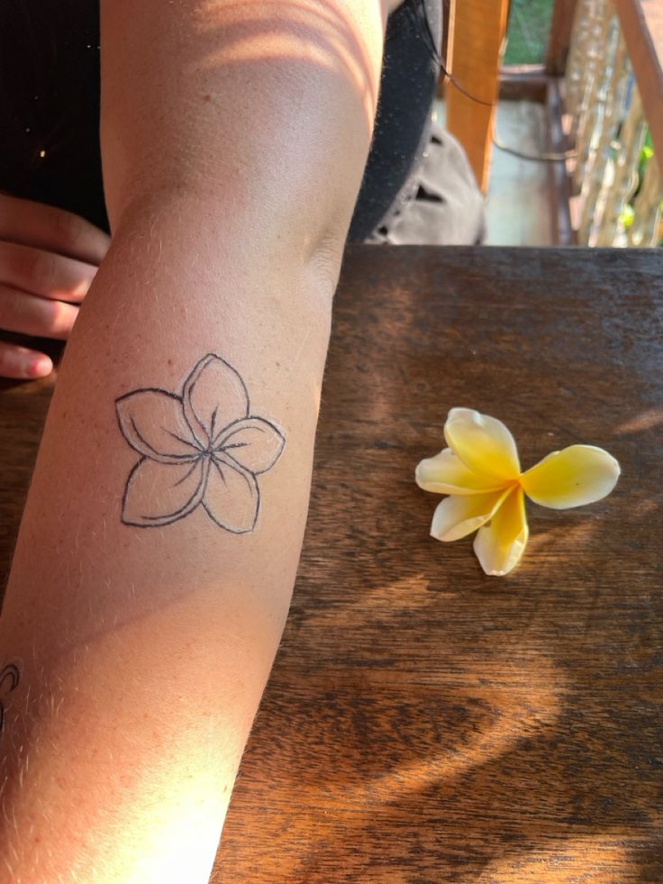 a person with a tattoo on their arm next to a flower