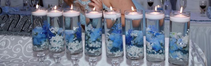 there are many candles in the glass vases