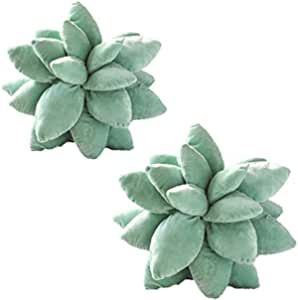 two green plant shaped cushions sitting next to each other on top of a white surface