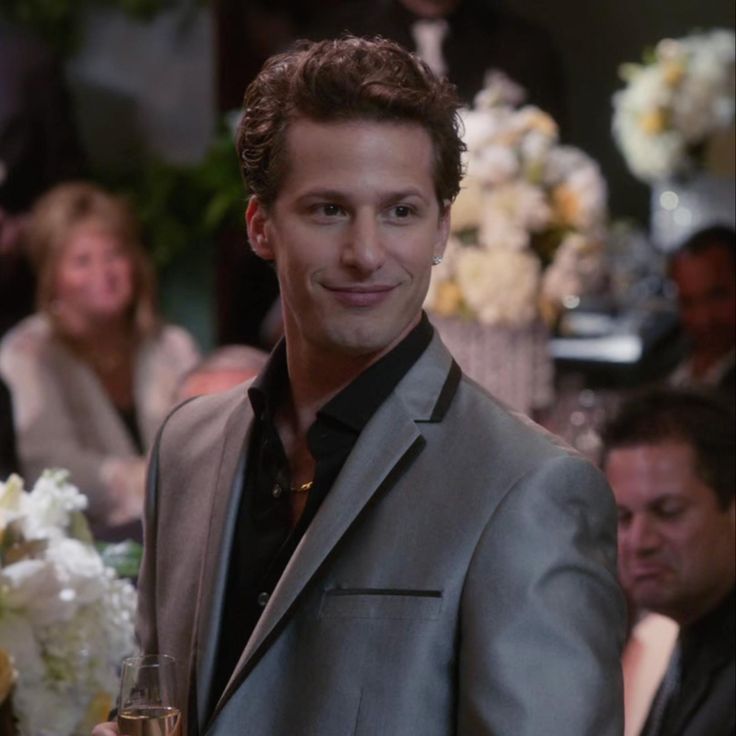 a man in a suit and tie standing next to a table with flowers on it