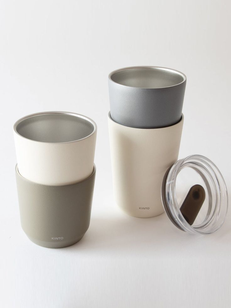 three cups with lids are sitting next to each other on a white surface, one is empty and the other has a lid