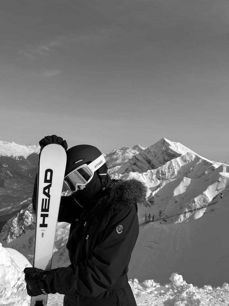 a person standing on top of a snow covered slope holding a snowboard in their hand