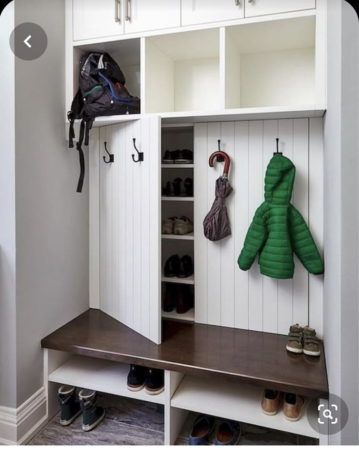 a coat rack with two coats hanging on it's sides and some shoes underneath