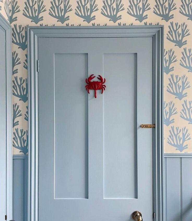 a blue door with a red crab on the handle and wallpaper in the background