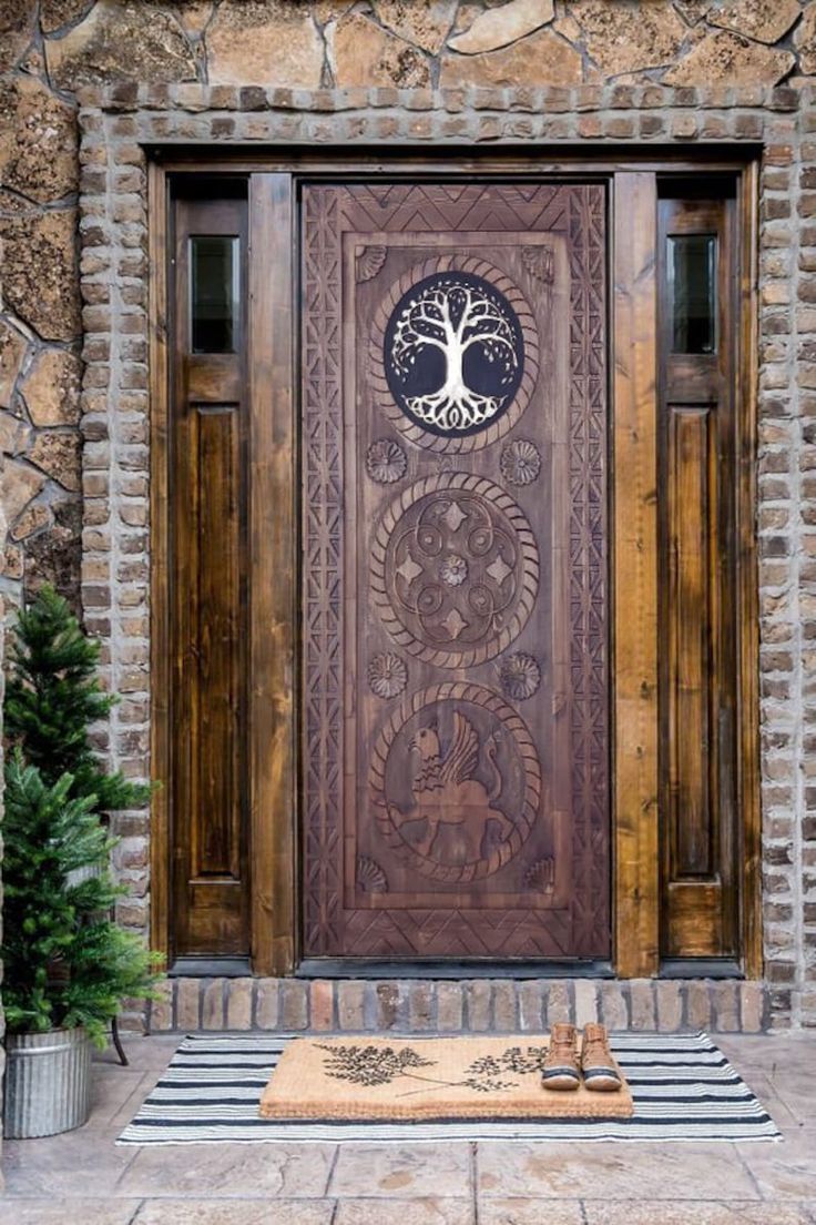 a wooden door with a tree on the front and side panel, surrounded by stone walls