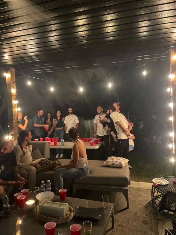 a group of people sitting around in a room with lights on the ceiling and couches