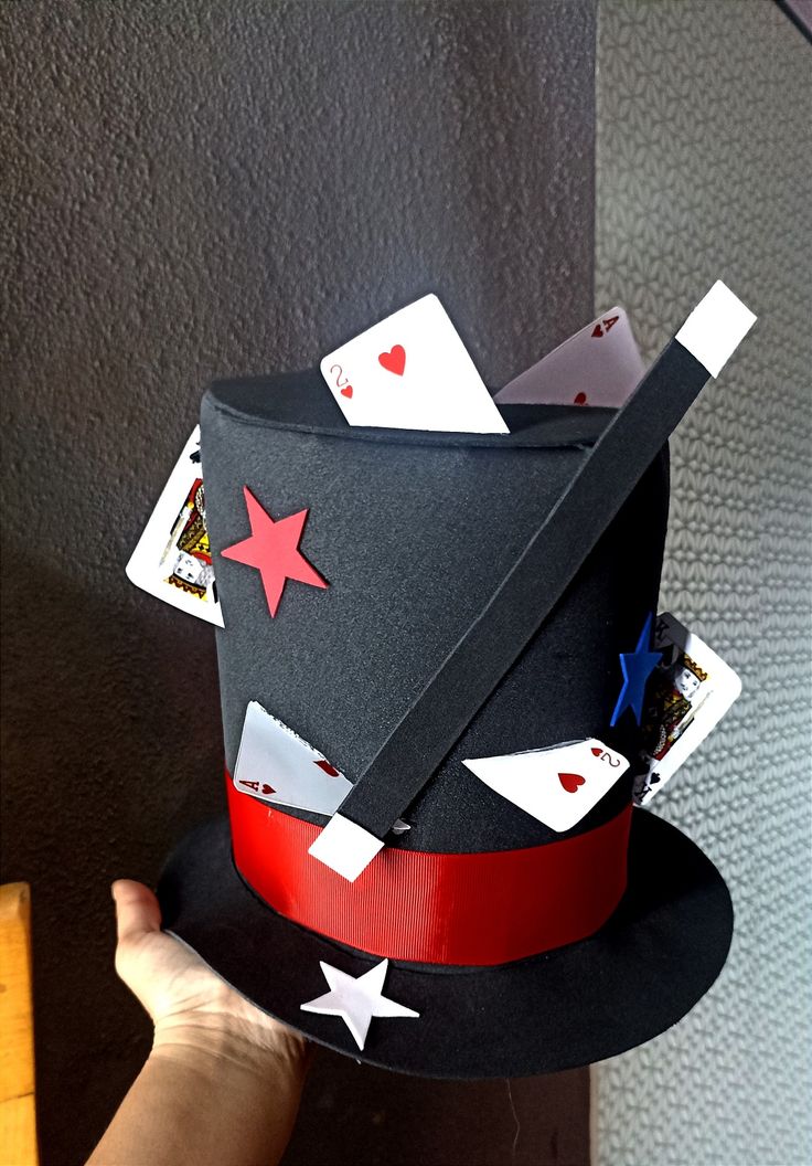 a hat with playing cards on it is being held by a person's hand