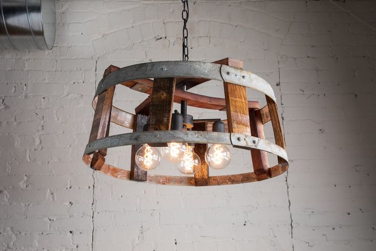 an old barrel chandelier hanging from a brick wall with light bulbs in it