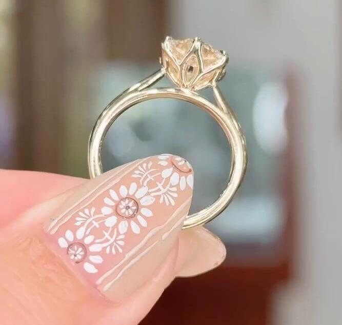 a close up of a person's hand holding a ring with flowers on it