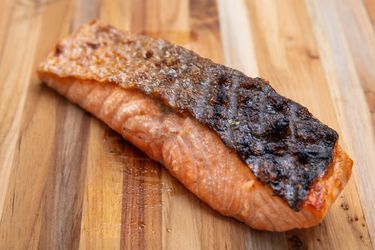 a piece of salmon sitting on top of a wooden cutting board