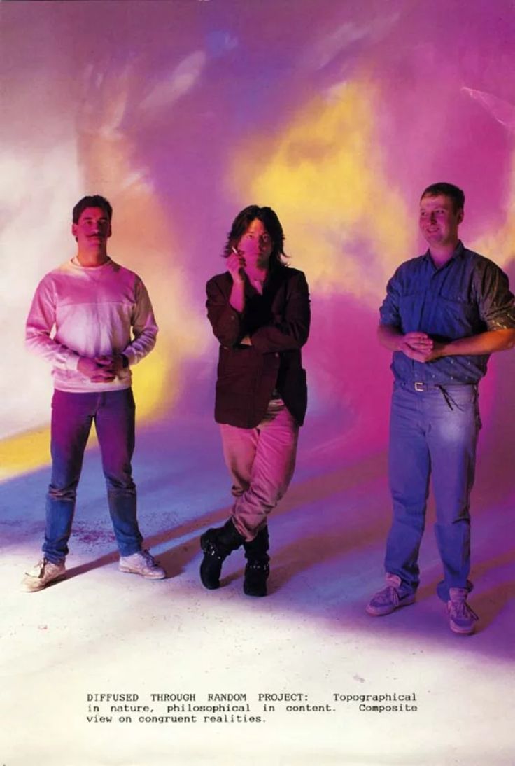 three men standing next to each other in front of a purple background