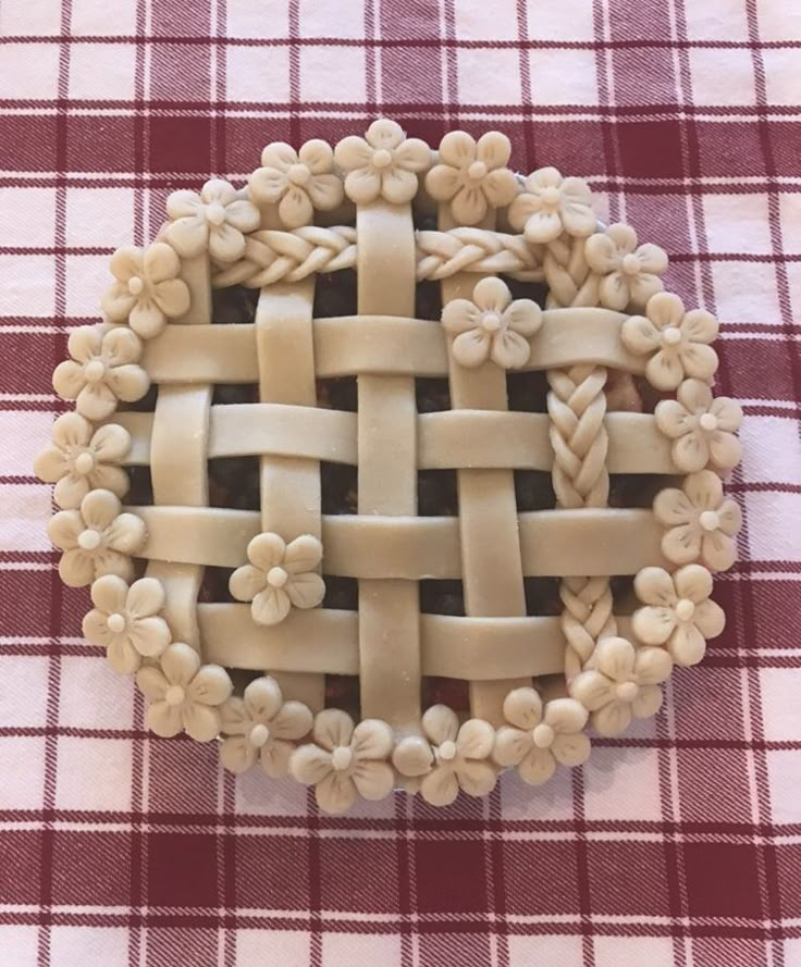 a close up of a pie on a checkered table cloth with flowers in the center