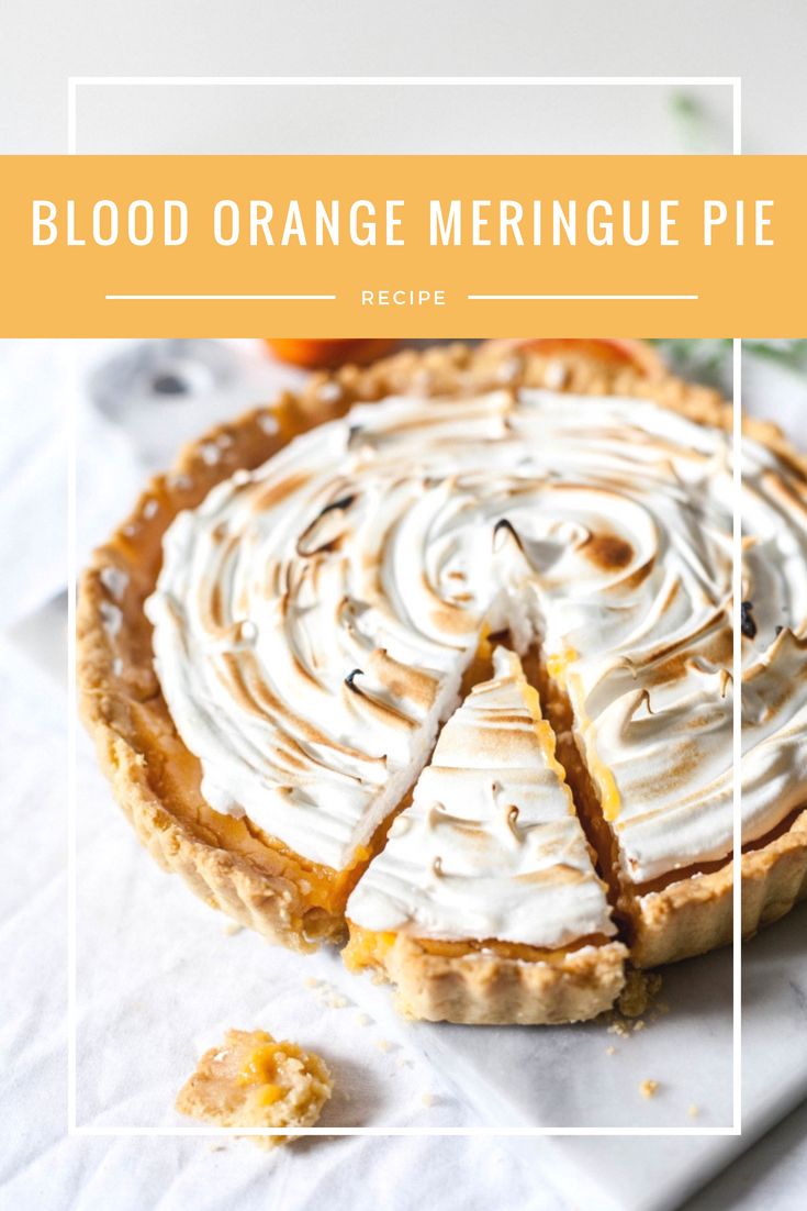 a pie with white frosting sitting on top of a table next to an orange slice