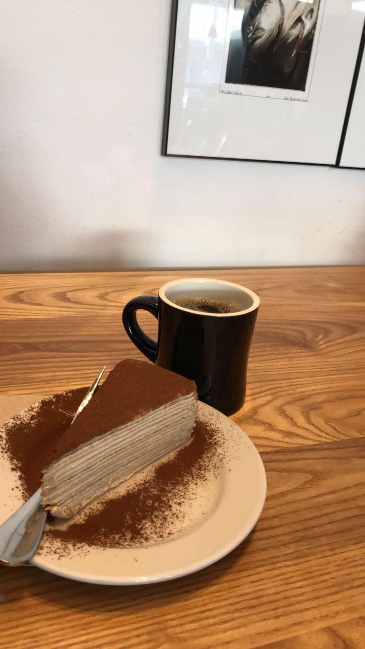 a piece of cake on a plate next to a cup of coffee