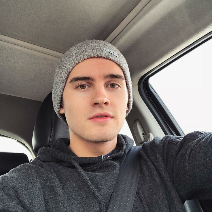 a young man wearing a beanie sitting in the back seat of a car