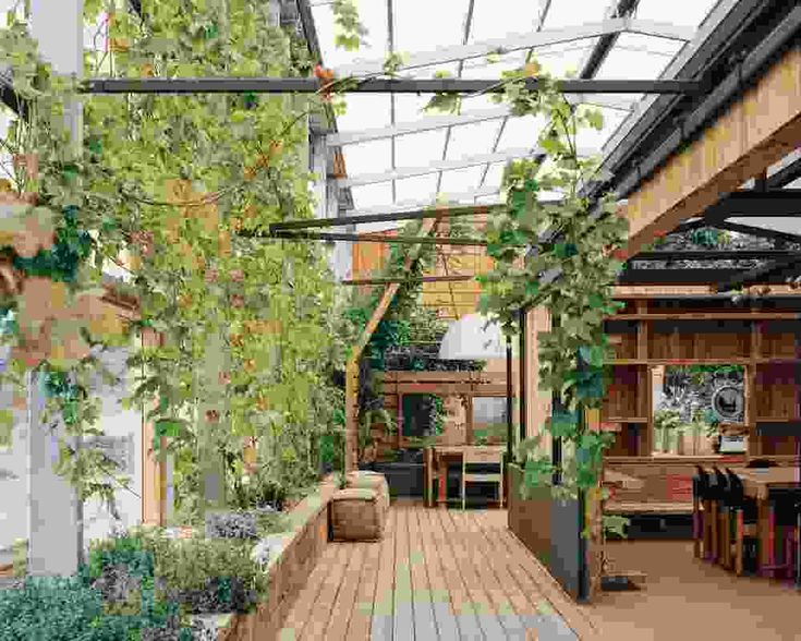 an outdoor room with wooden flooring and lots of greenery