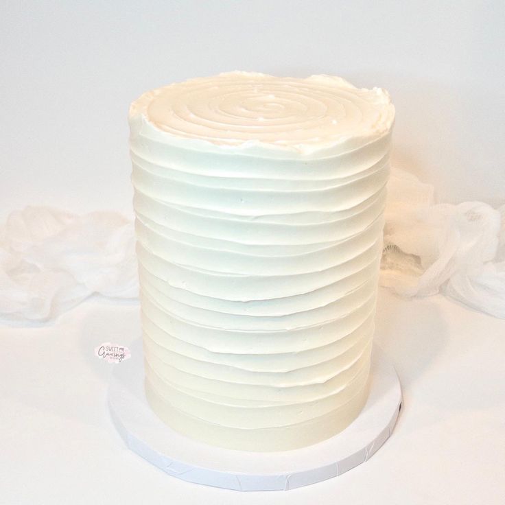 a white frosted cake sitting on top of a table next to a roll of toilet paper