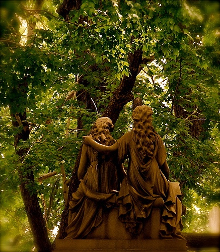 two statues sitting next to each other in front of trees