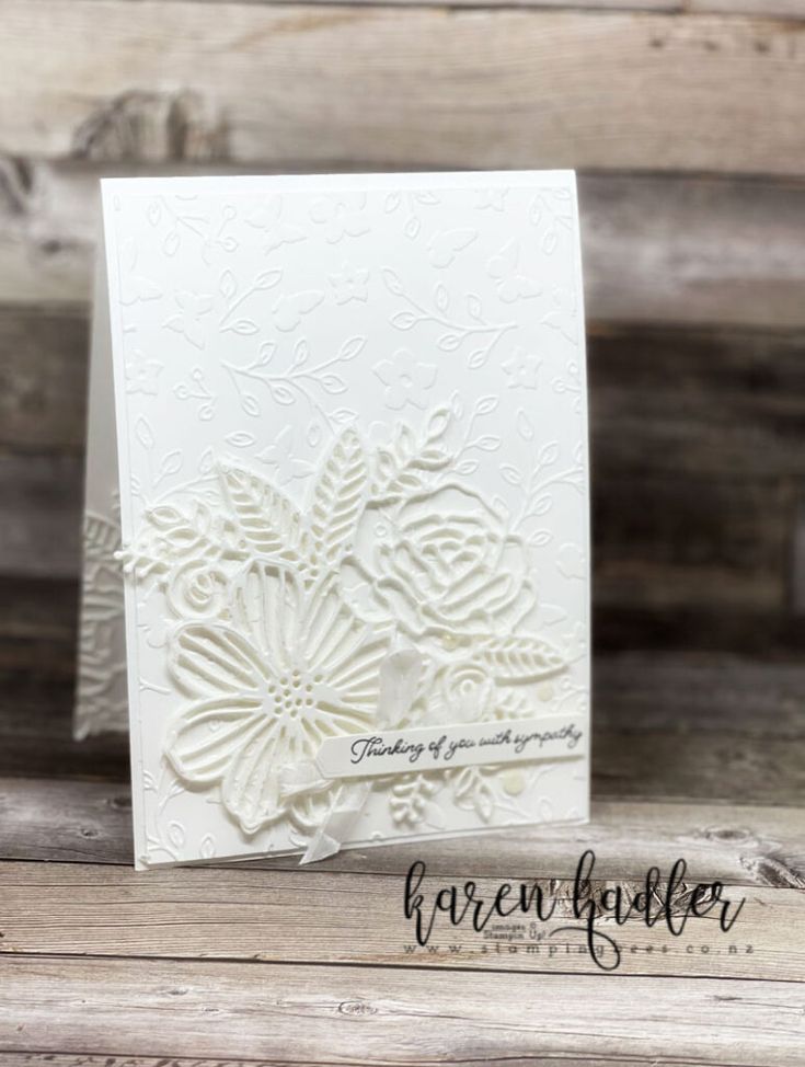 a white card with an intricate design on the front and back, sitting on a wooden surface