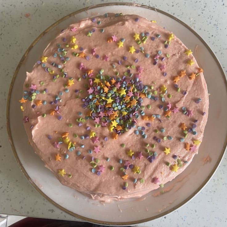 a cake with pink frosting and sprinkles sitting on top of a white plate