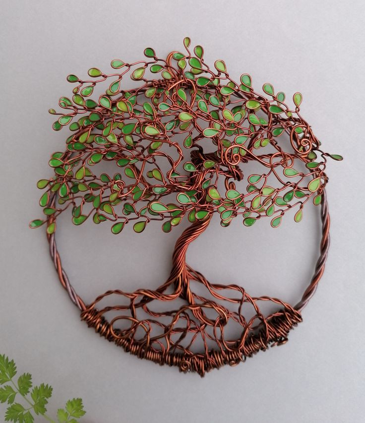 a wire tree sculpture with green leaves on it's sides and roots in the center