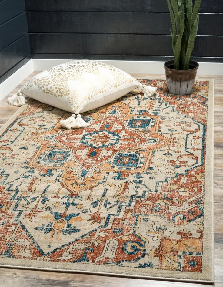 a large rug with an orange and blue pattern on the floor next to a potted plant