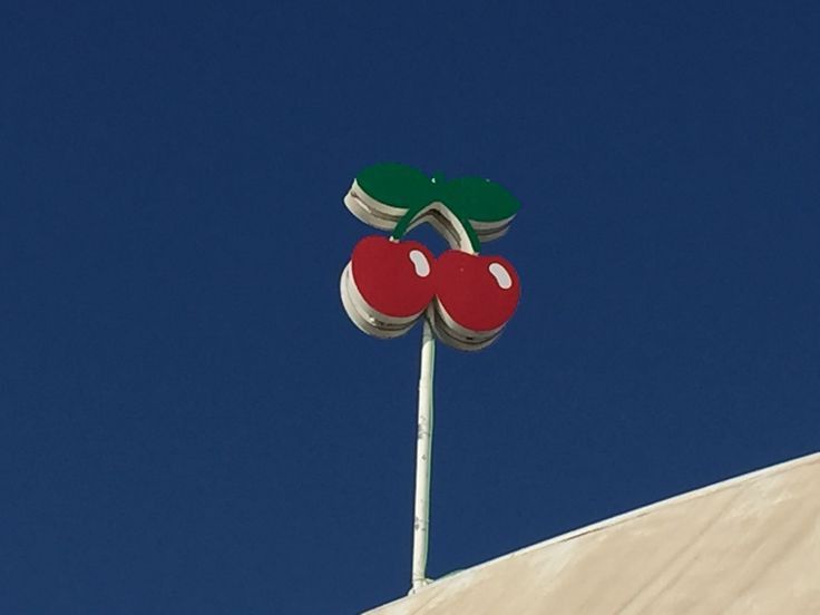 a street sign with two cherries on it's top against a blue sky