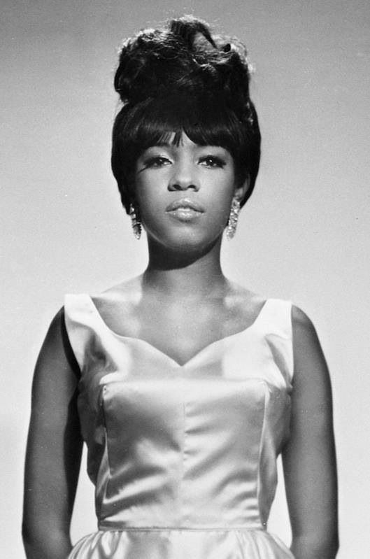 an old photo of a woman in a white dress with her hair styled into a bun