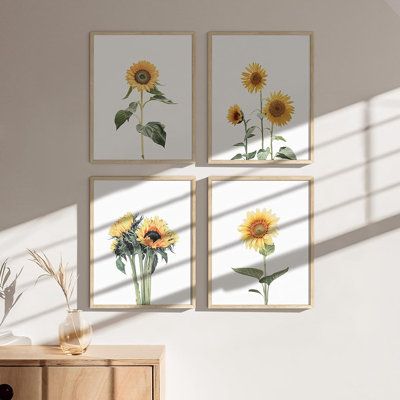 three sunflowers are displayed on the wall above a dresser in a room with white walls